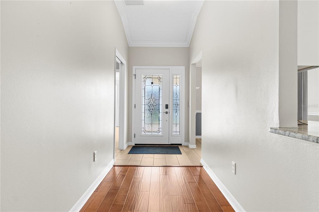 An entryway features hardwood flooring, a tiled foyer, and a white front door with glass — 589 SHERWOOD STREET, THE VILLAGES, FL
