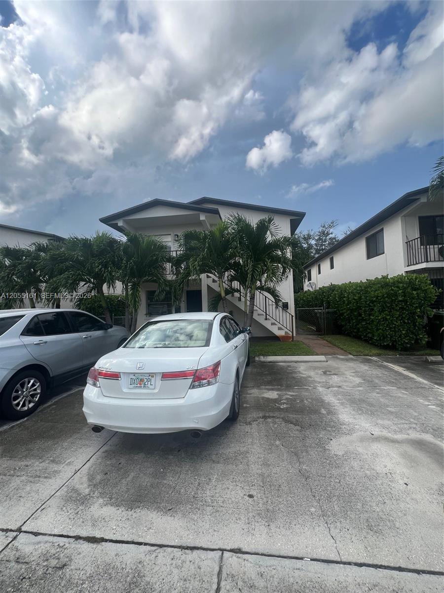 A white sedan is parked in front of a two-story apartment building with palm trees — 467 E 13th St # 467A, Hialeah FL 33010, HIALEAH, FL
