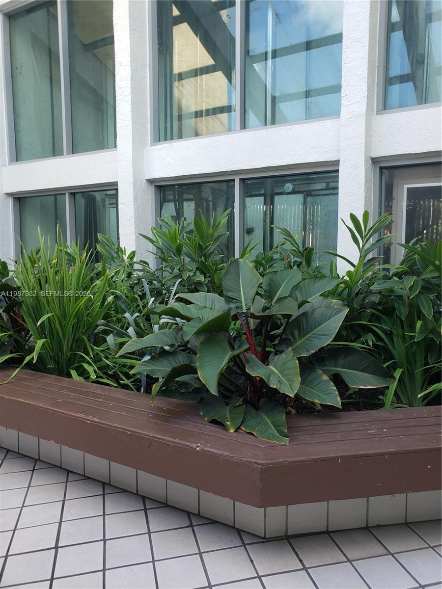 A raised wooden planter box filled with various green plants sits before large glass windows — 11800 SW 18th St # 4, Miami FL 33175, MIAMI, FL