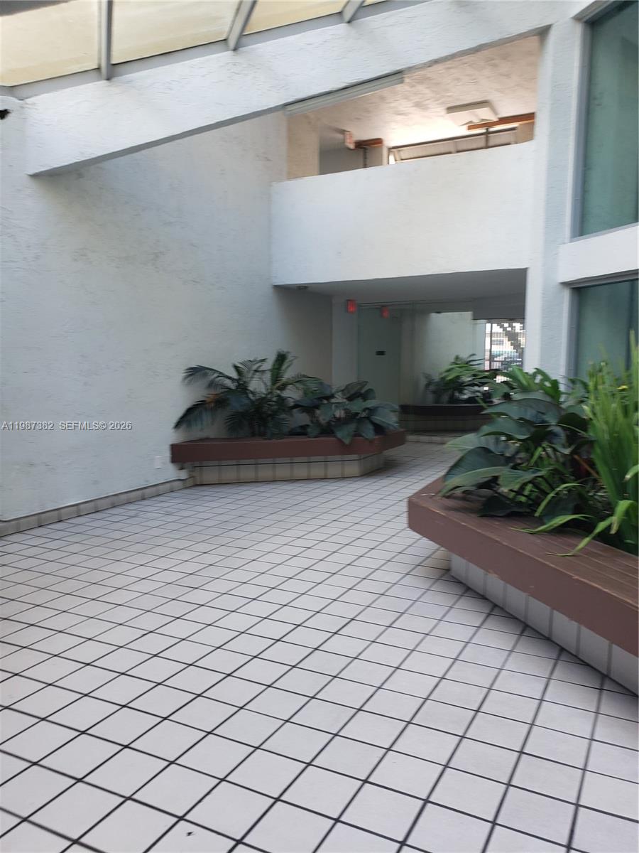 An indoor atrium features white tiled floors, built-in planters with greenery, and a skylight ceiling — 11800 SW 18th St # 4, Miami FL 33175, MIAMI, FL