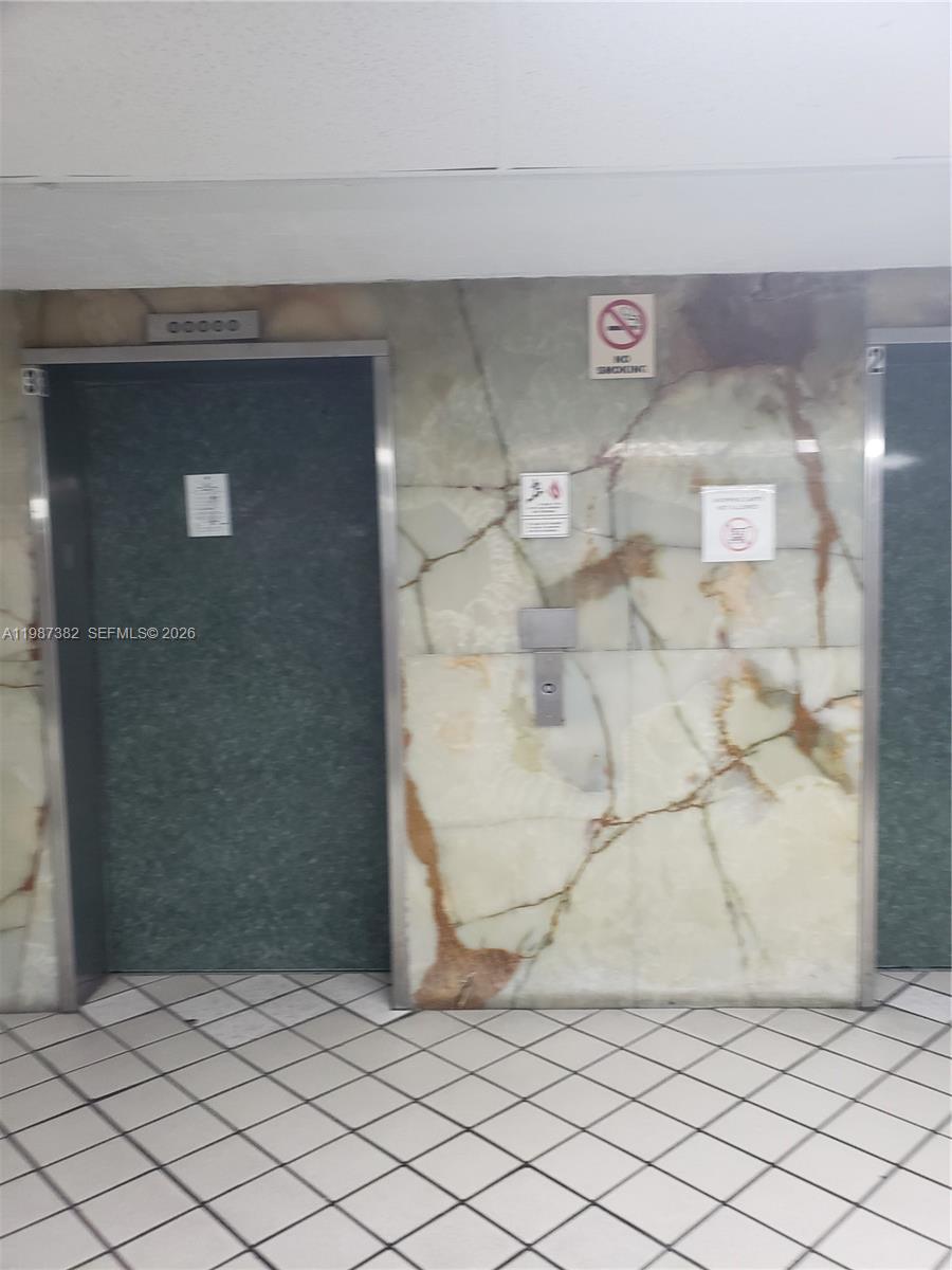 Two elevator doors are set into a wall with light-colored, veined marble paneling — 11800 SW 18th St # 4, Miami FL 33175, MIAMI, FL