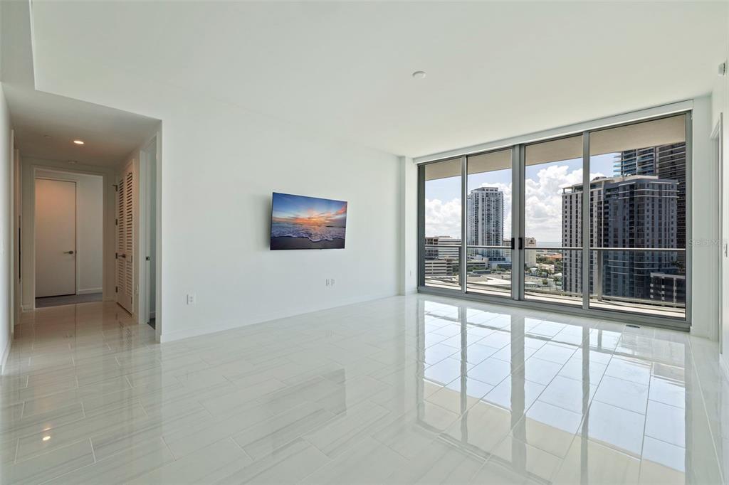 A bright, modern living room with white tile floors, a wall-mounted television, and floor-to-ceiling windows — 400 CENTRAL AVENUE UNIT 1105, ST PETERSBURG, FL