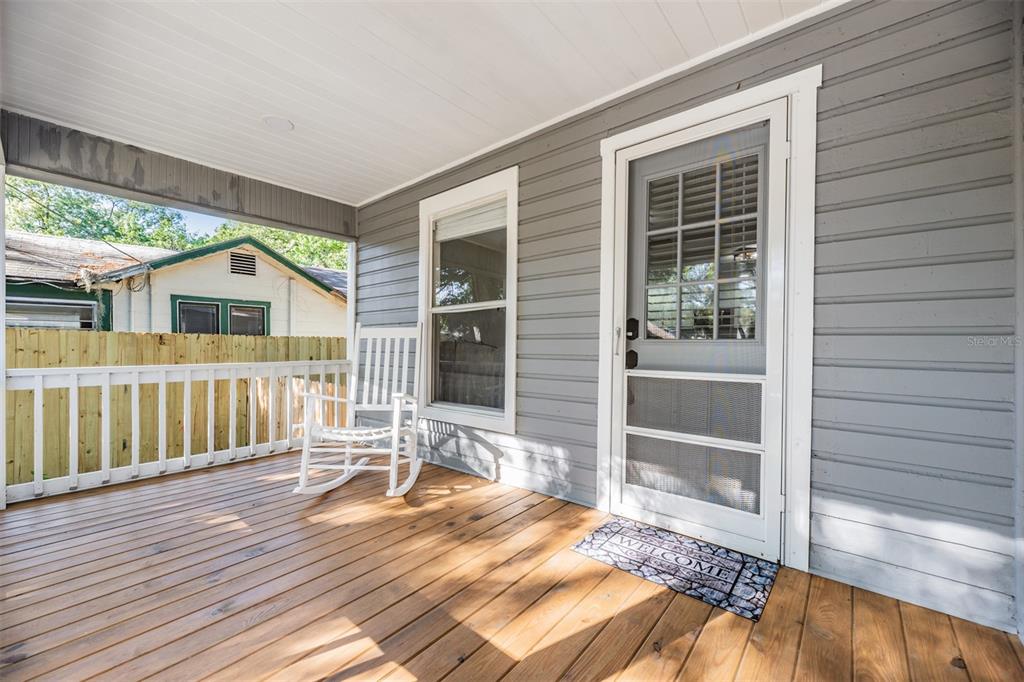 A wooden porch features a white rocking chair, a screen door, and gray siding — 4206 N 13TH STREET, TAMPA, FL