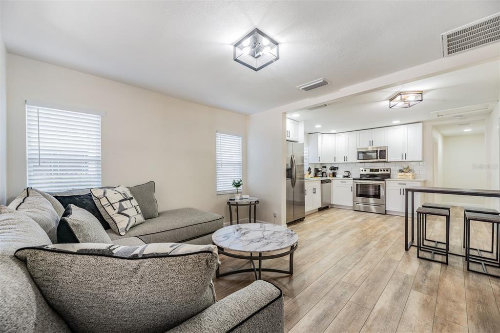A living room with a grey sectional sofa opens into a kitchen with white cabinets — 4206 N 13TH STREET, TAMPA, FL
