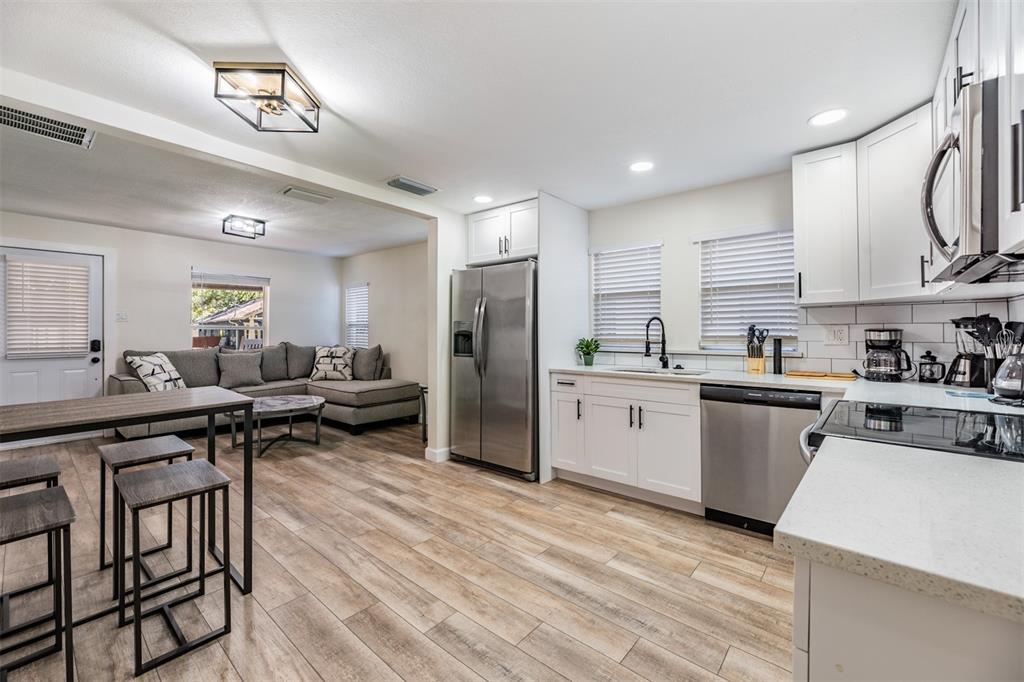 A modern kitchen with white cabinets and stainless steel appliances opens into a living area — 4206 N 13TH STREET, TAMPA, FL