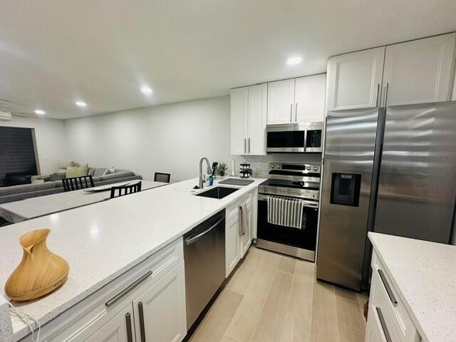 A modern kitchen features white cabinets, stainless steel appliances, and a long quartz countertop — 2601 NE 3rd Court # 1050, Boynton Beach FL 33435, BOYNTON BEACH, FL