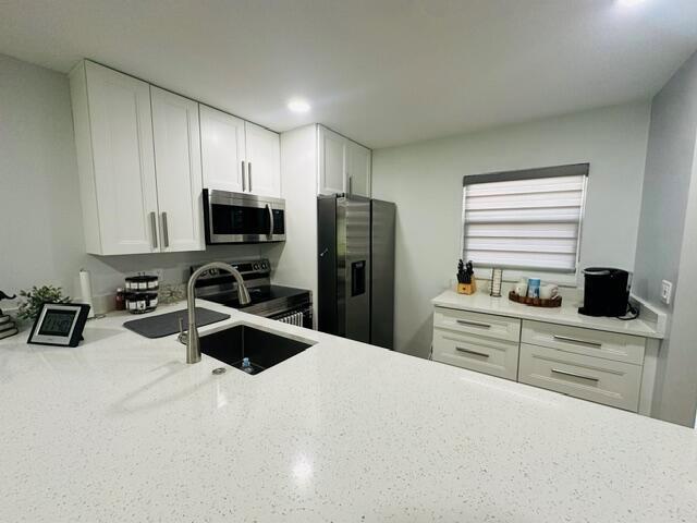 A modern kitchen features white cabinetry, stainless steel appliances, and a white quartz countertop — 2601 NE 3rd Court # 1050, Boynton Beach FL 33435, BOYNTON BEACH, FL