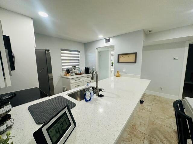 A modern kitchen features white cabinetry, a quartz island countertop, and stainless steel appliances — 2601 NE 3rd Court # 1050, Boynton Beach FL 33435, BOYNTON BEACH, FL