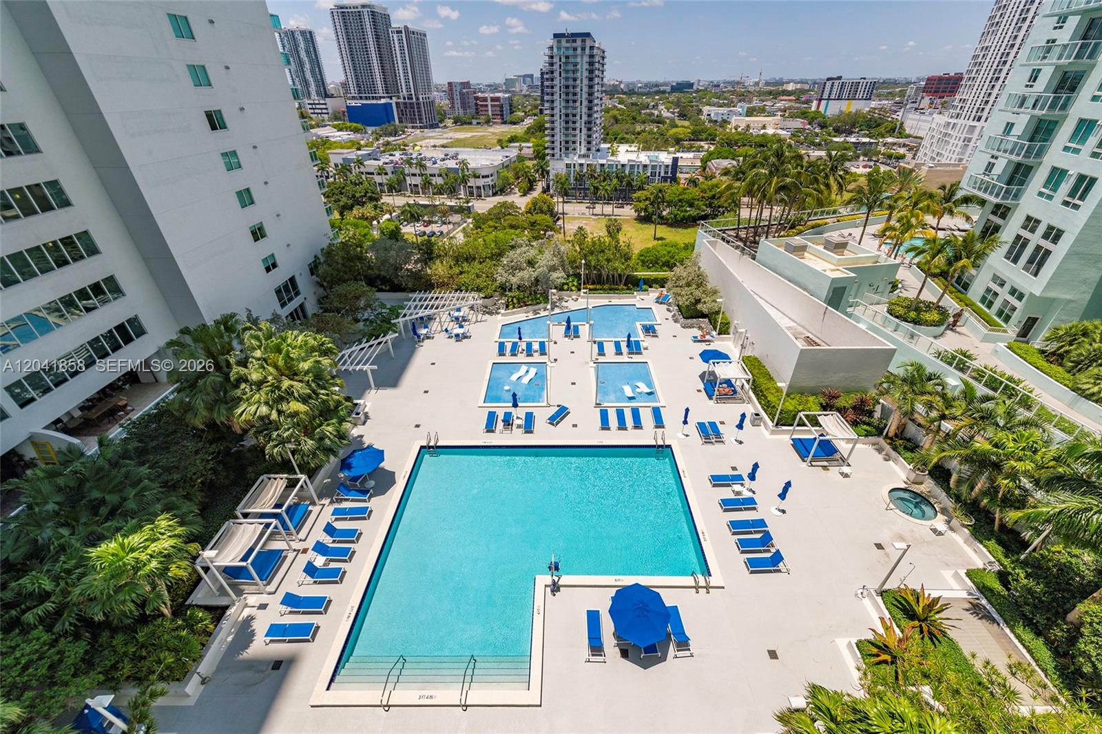 An aerial view shows a large swimming pool deck with lounge chairs and cabanas — 1800 N Bayshore Dr # 1806, Miami FL 33132, MIAMI, FL