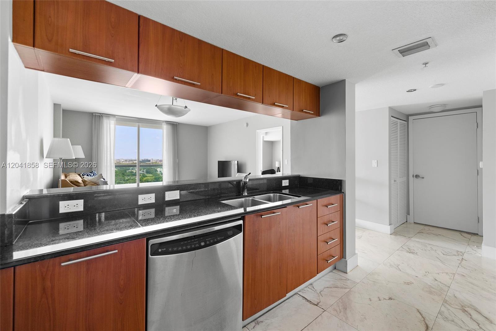 A kitchen features wood cabinets, black granite countertops, stainless steel appliances, and marble-look tile flooring — 1800 N Bayshore Dr # 1806, Miami FL 33132, MIAMI, FL