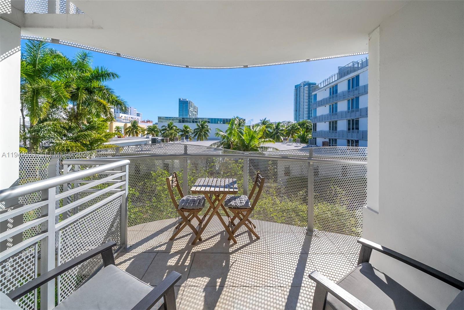 A balcony features a small wooden table with two chairs and a metal railing — 2155 Washington Ct # 303, Miami Beach FL 33139, MIAMI BEACH, FL