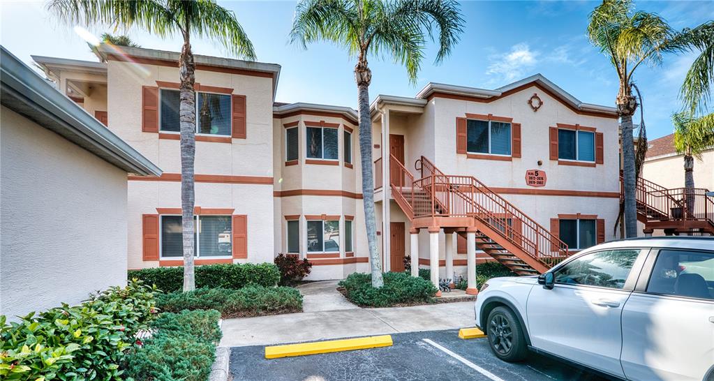 A two-story apartment building with stucco walls, brown shutters, and an exterior staircase — 3980 MEDITERRANEA CIRCLE UNIT 522, SARASOTA, FL