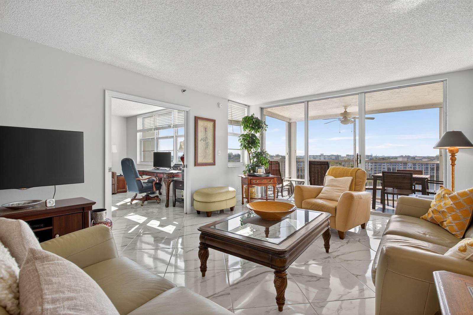 A living room with marble floors, a glass-topped coffee table, and a balcony with views — 2900 N Course Drive # 905, Pompano Beach FL 33069, POMPANO BEACH, FL
