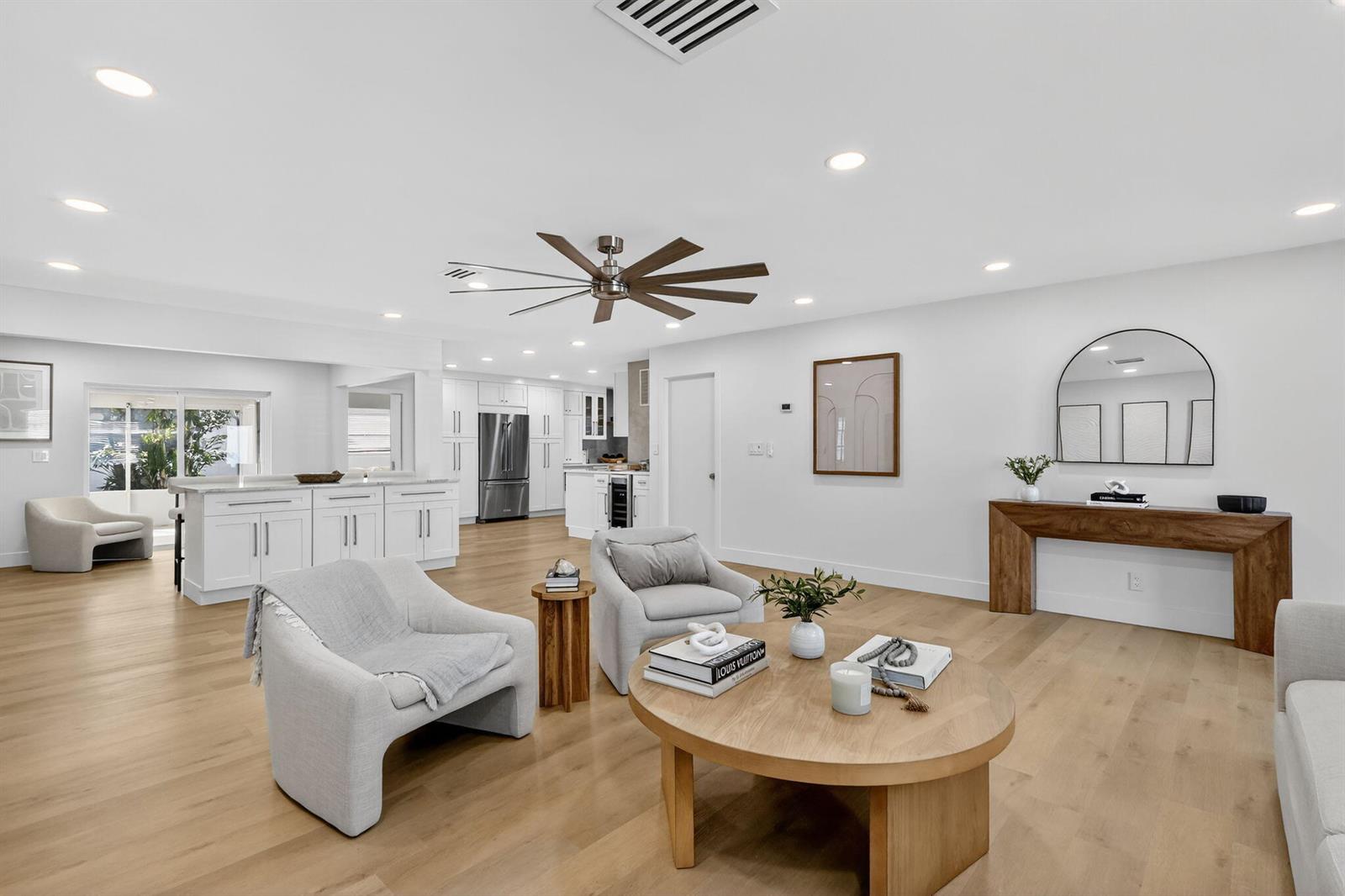 A bright, open-concept living room and kitchen featuring light wood floors and modern white cabinetry — 2206 SW 20th Way, Boynton Beach FL 33426, BOYNTON BEACH, FL