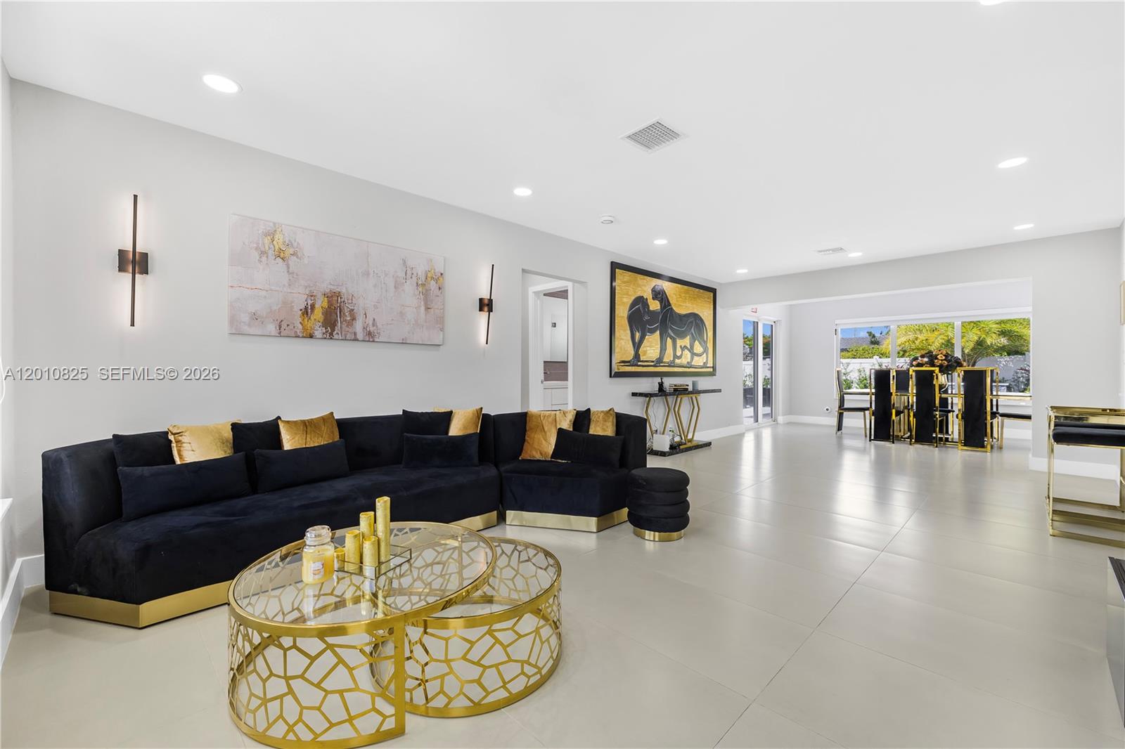 A modern living room features a black sectional sofa, gold coffee tables, and tile flooring — 1104 N 13th Ter, Hollywood FL 33019, HOLLYWOOD, FL