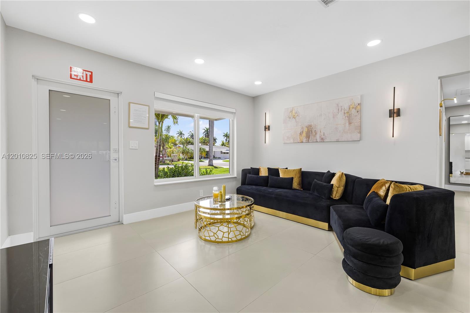 A modern living room features a black sectional sofa, gold accents, and a large window — 1104 N 13th Ter, Hollywood FL 33019, HOLLYWOOD, FL