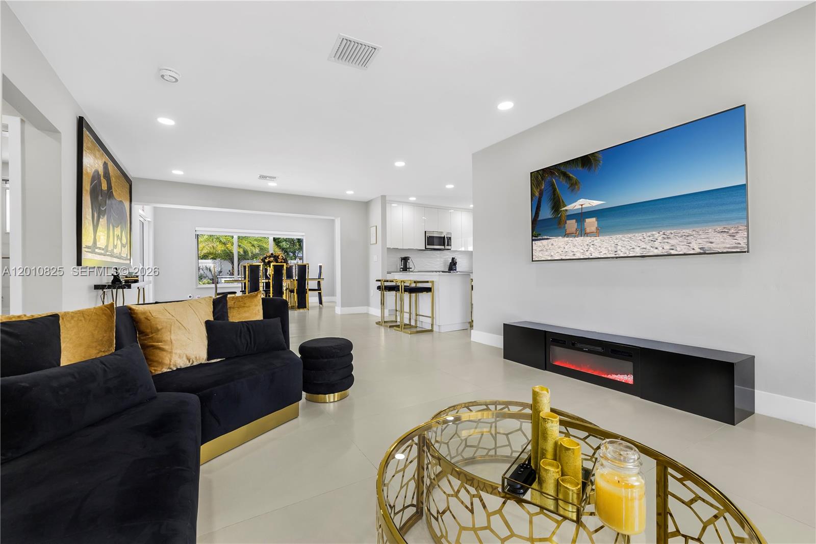 A modern living room features a black sofa, gold accents, and a wall-mounted television — 1104 N 13th Ter, Hollywood FL 33019, HOLLYWOOD, FL