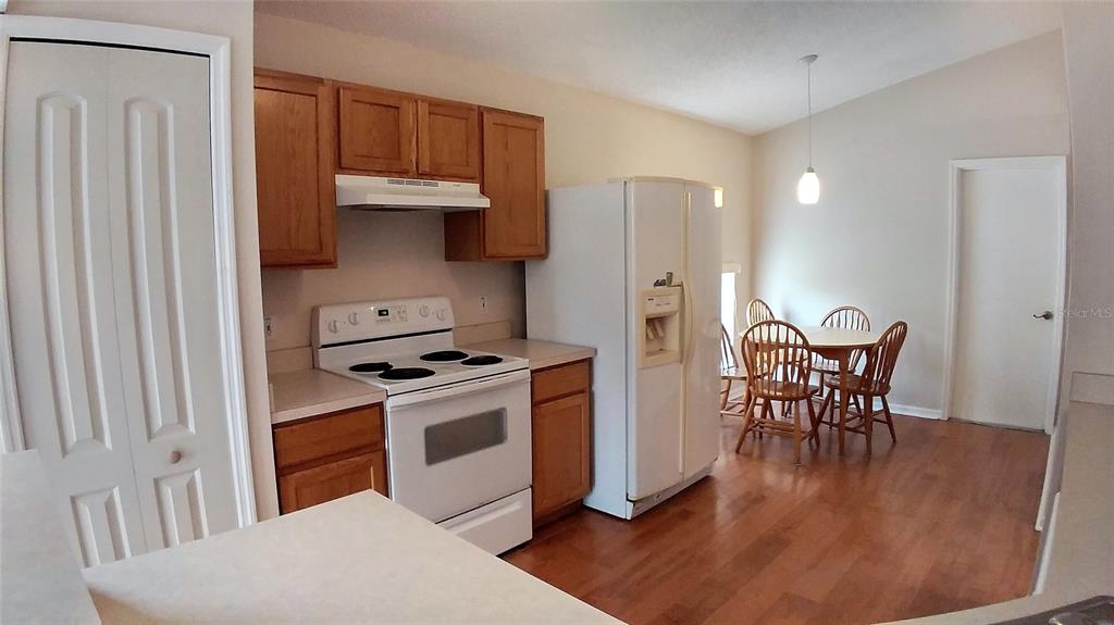 A kitchen with wood cabinets, white appliances, and a dining area with hardwood floors — 3842 STONEFIELD DRIVE, ORLANDO, FL