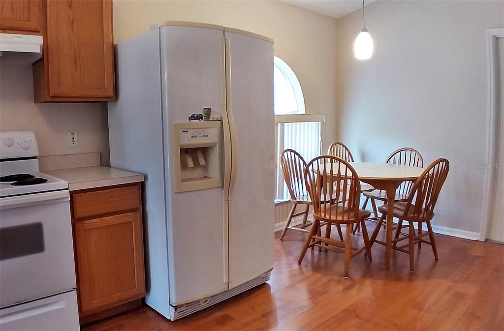 A kitchen with wooden cabinets, a white refrigerator, and a dining table with four chairs — 3842 STONEFIELD DRIVE, ORLANDO, FL