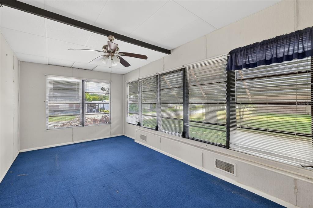 A sunroom with blue carpeting, a ceiling fan, and large windows with horizontal blinds — 1625 HILTON HEAD BOULEVARD, LADY LAKE, FL