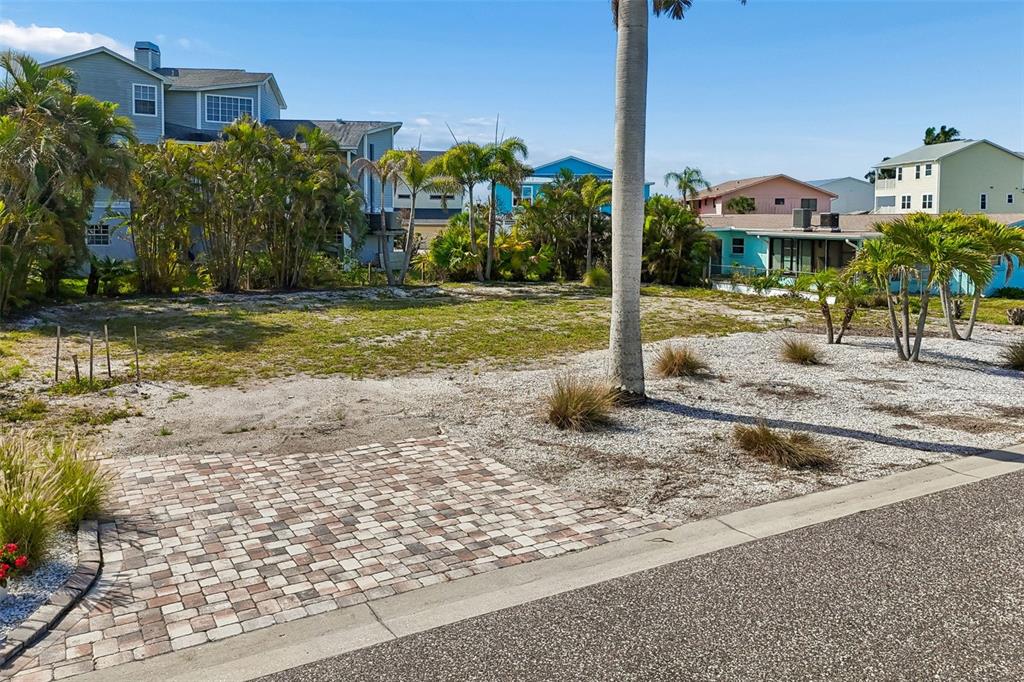 A vacant, grassy residential lot features a paved driveway section and several palm trees — 211 176TH TERRACE DRIVE E, REDINGTON SHORES, FL