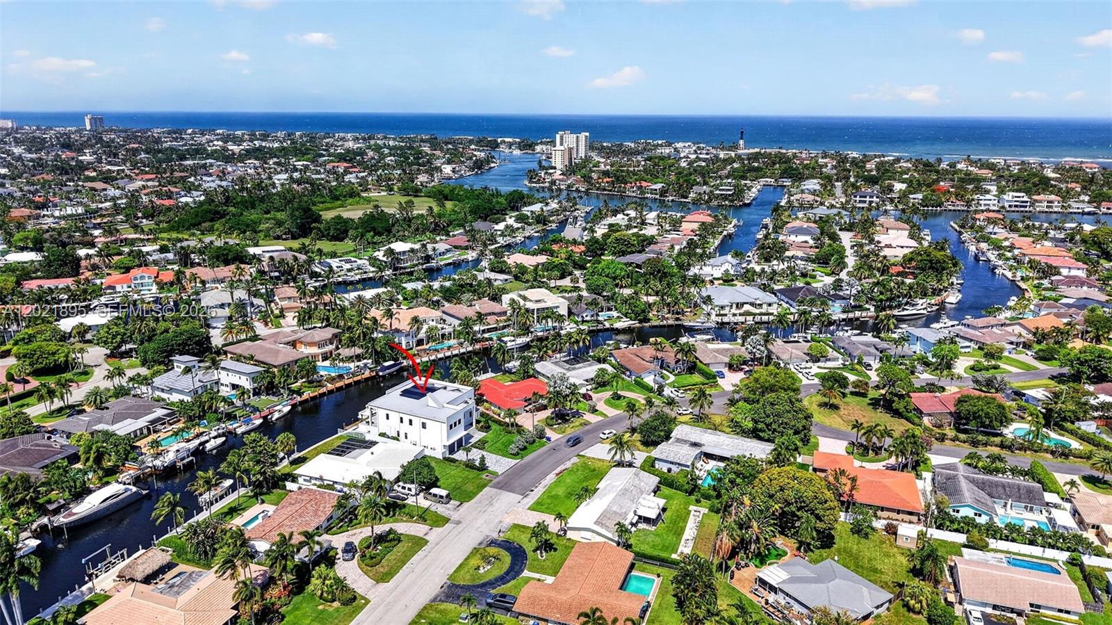 An aerial view shows a white house with solar panels situated along a canal — 2751 NE 22nd Ct, Pompano Beach FL 33062, POMPANO BEACH, FL