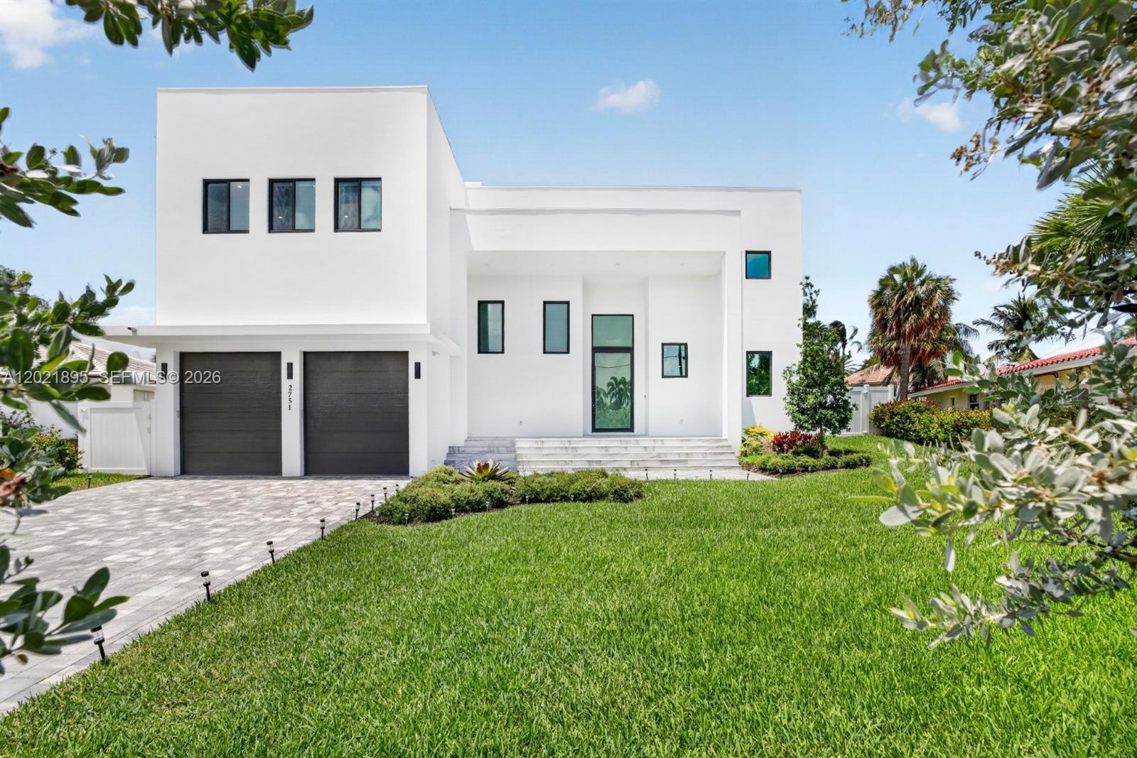 A modern two-story white house features a two-car garage and a landscaped front lawn — 2751 NE 22nd Ct, Pompano Beach FL 33062, POMPANO BEACH, FL