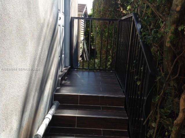 An exterior staircase with dark wood-look tile steps and a black metal railing — 3350 SW 3rd St, Miami FL 33135, MIAMI, FL