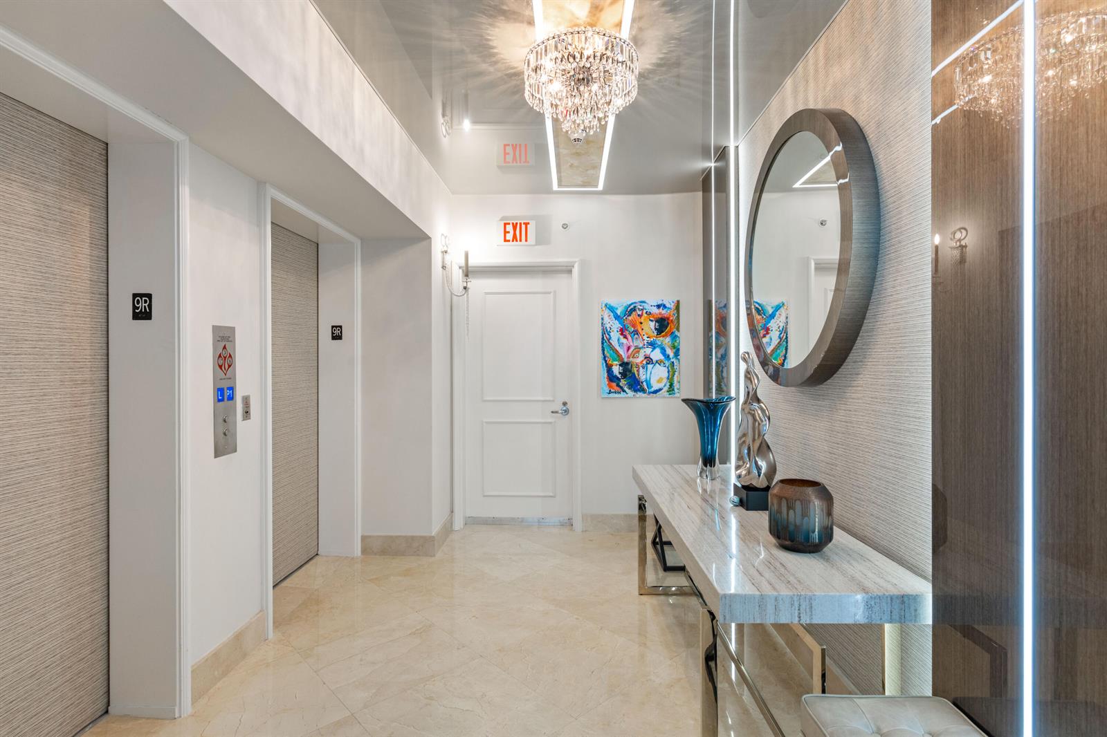 A modern building hallway features a marble console table, a round mirror, and elevator doors — 3101 S Ocean Drive # 901, Hollywood FL 33019, HOLLYWOOD, FL