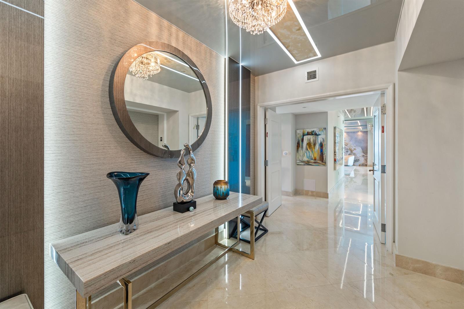 A modern entryway features a marble console table, a circular mirror, and polished tile floors — 3101 S Ocean Drive # 901, Hollywood FL 33019, HOLLYWOOD, FL