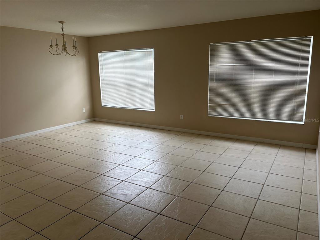 An empty room features light brown wood-look flooring and beige walls with white baseboards — 15628 PERDIDO DRIVE, ORLANDO, FL