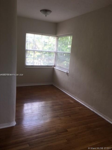 An empty bedroom features hardwood floors, beige walls, and corner windows with horizontal blinds — 1002 SW 37th Ave # 3, Coral Gables FL 33127, CORAL GABLES, FL