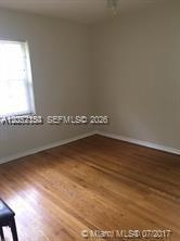 An empty room features light-colored walls, a single window, and polished hardwood flooring — 1002 SW 37th Ave # 3, Coral Gables FL 33127, CORAL GABLES, FL