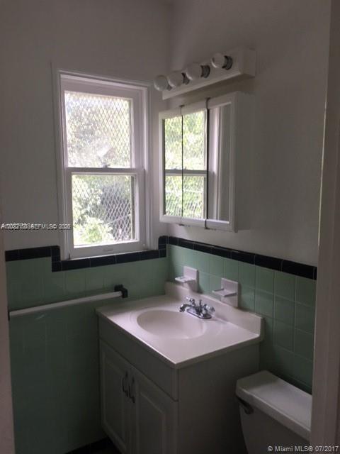 A bathroom features a white vanity, a medicine cabinet, and green wall tiles with black trim — 1002 SW 37th Ave # 3, Coral Gables FL 33127, CORAL GABLES, FL