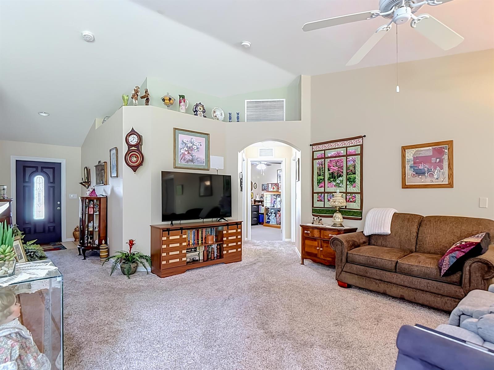 A living room features a television on a wooden console, a brown sofa, and carpet — 2610 53rd Street W, Lehigh Acres FL 33971, LEHIGH ACRES, FL
