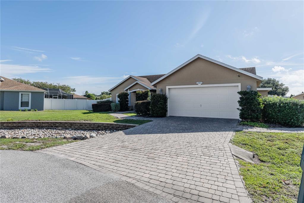 A single-story house with a beige exterior, a two-car garage, and a paved driveway — 205 THOMAS COURT, WINTER HAVEN, FL