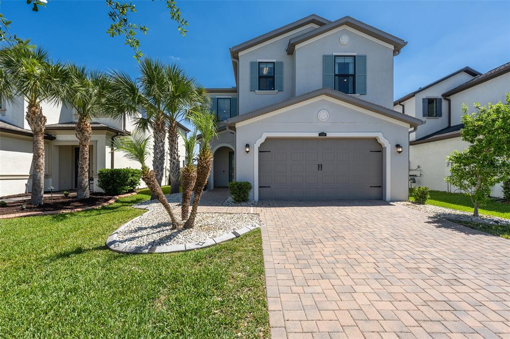 A two-story house with a gray garage, light-colored stucco exterior, and a paved driveway — 4790 TRAMANTO LANE, WESLEY CHAPEL, FL
