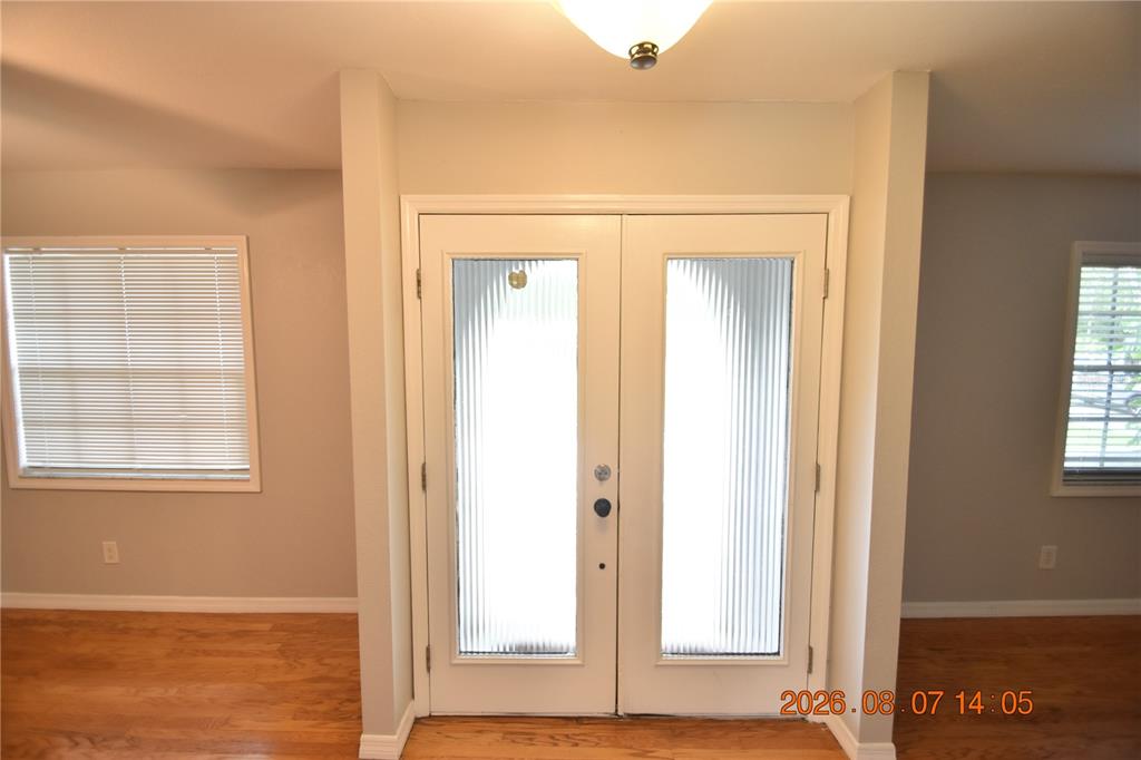 A bright entryway features white double doors with fluted glass panels and hardwood flooring — 3827 FROSTWOOD COURT, LAND O LAKES, FL