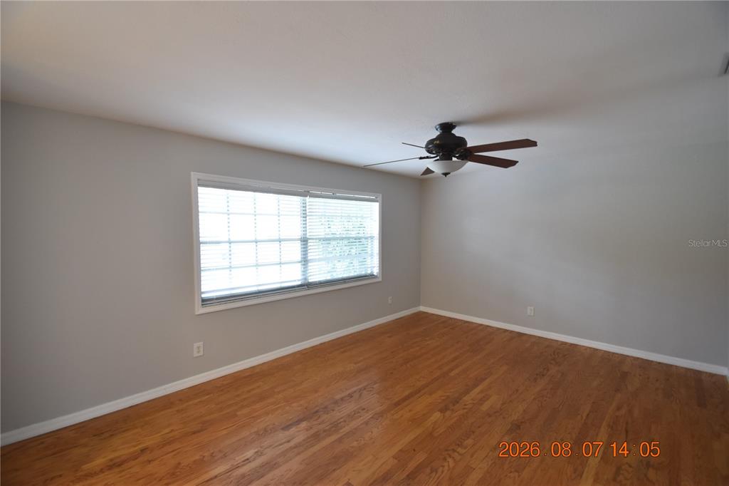 An empty bedroom features light gray walls, hardwood flooring, and a ceiling fan — 3827 FROSTWOOD COURT, LAND O LAKES, FL