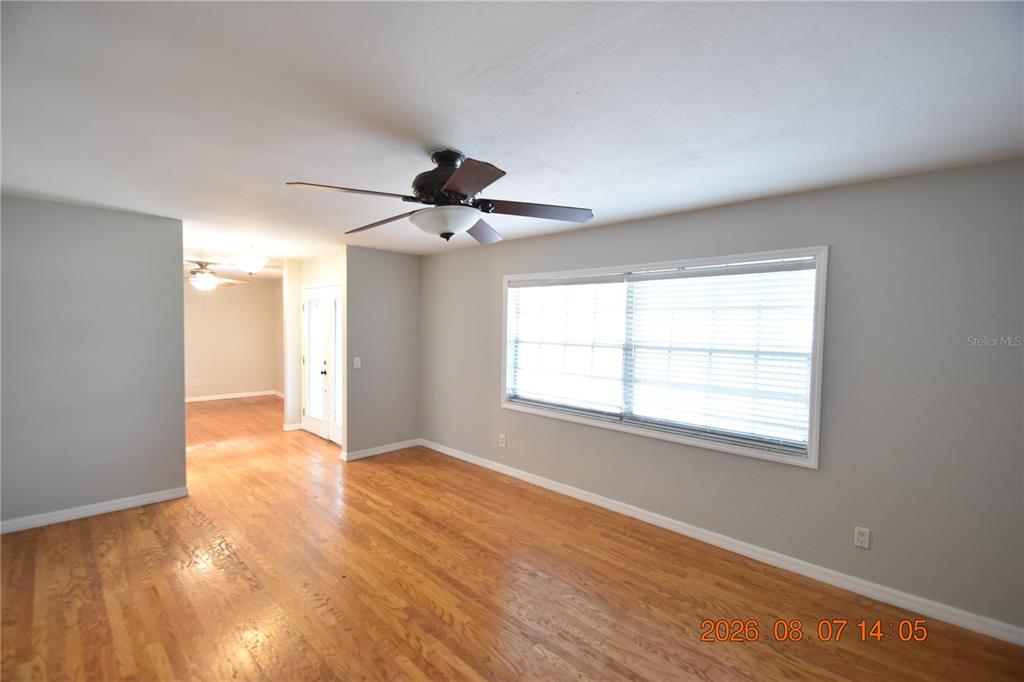 A living room features hardwood floors, a ceiling fan, and a large window with blinds — 3827 FROSTWOOD COURT, LAND O LAKES, FL