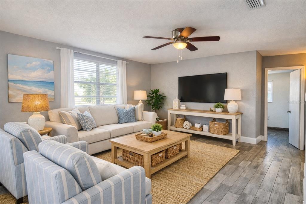 A living room features a beige sofa, two striped armchairs, a wooden coffee table, and television — 1806 JAMES STREET, SOUTH DAYTONA, FL