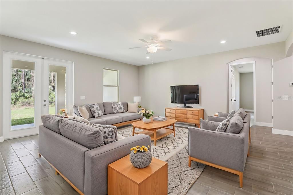 A living room features gray sofas, a wooden coffee table, and tile flooring — 3187 TOPSEY AVENUE SE, PALM BAY, FL