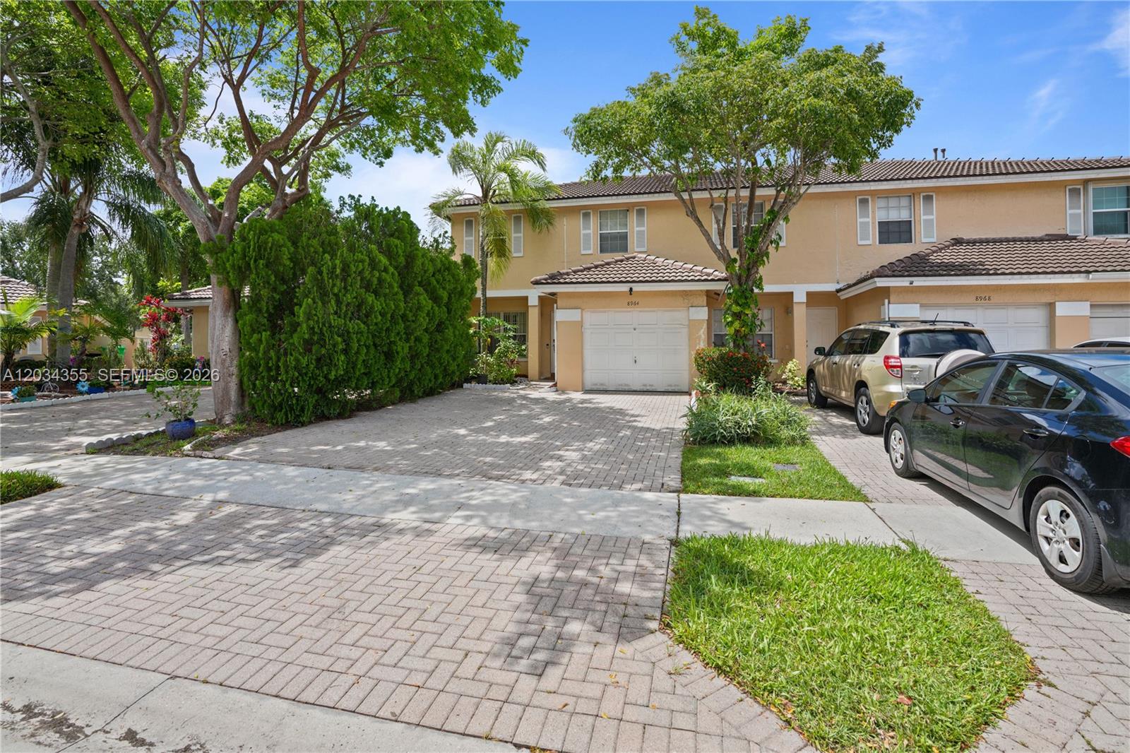 A two-story townhouse with a paved driveway, a single-car garage, and mature landscaping — 8964 NW 53rd Ct, Sunrise FL 33351, SUNRISE, FL
