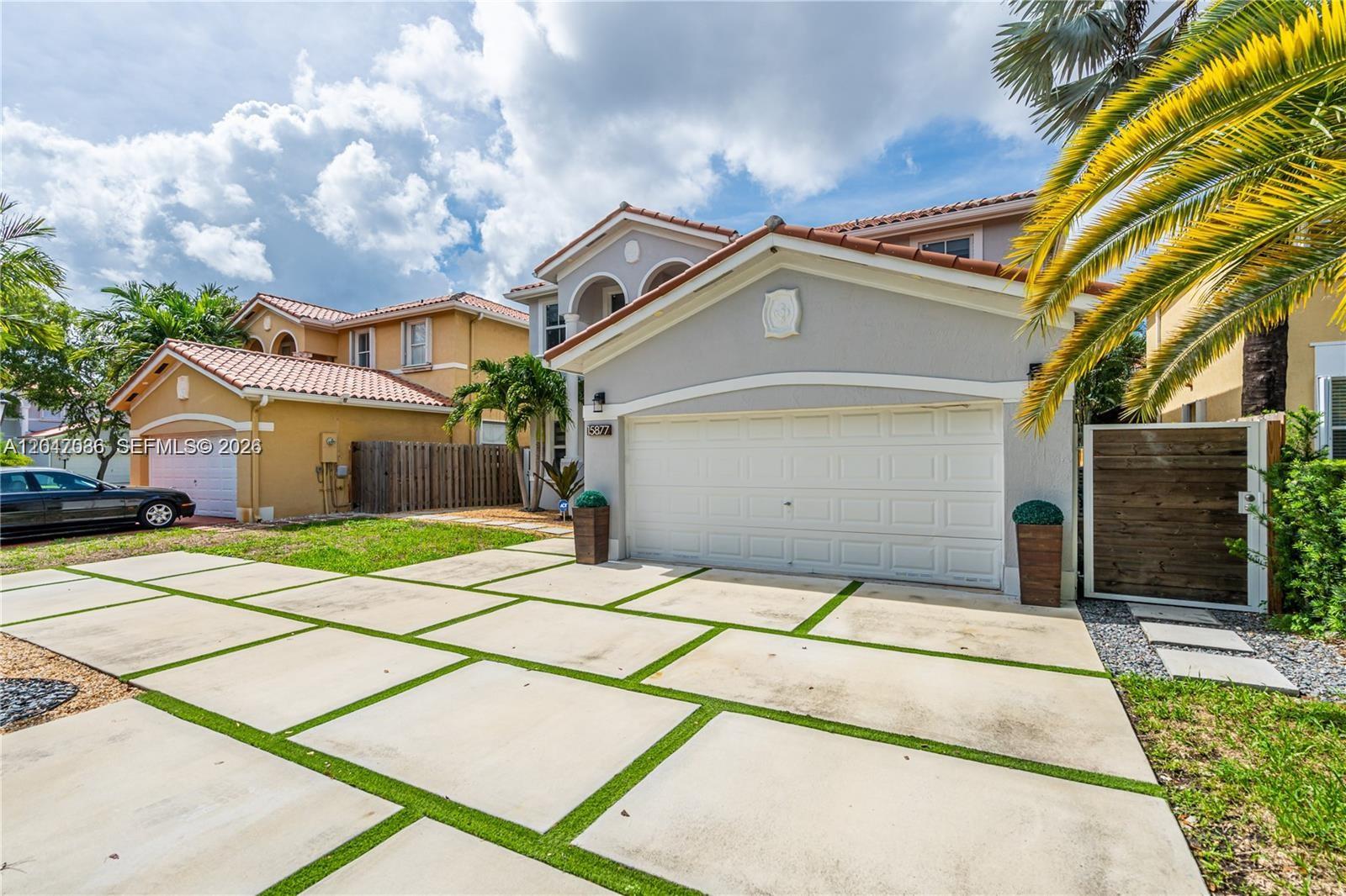 A two-story house with a white garage door and a concrete paver driveway with grass — 15877 SW 61st Way, Miami FL 33193, MIAMI, FL