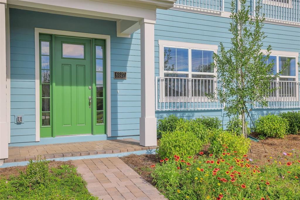 A light blue house exterior features a bright green front door and a brick walkway — 6527 TRAILBLAZE BEND, ST CLOUD, FL