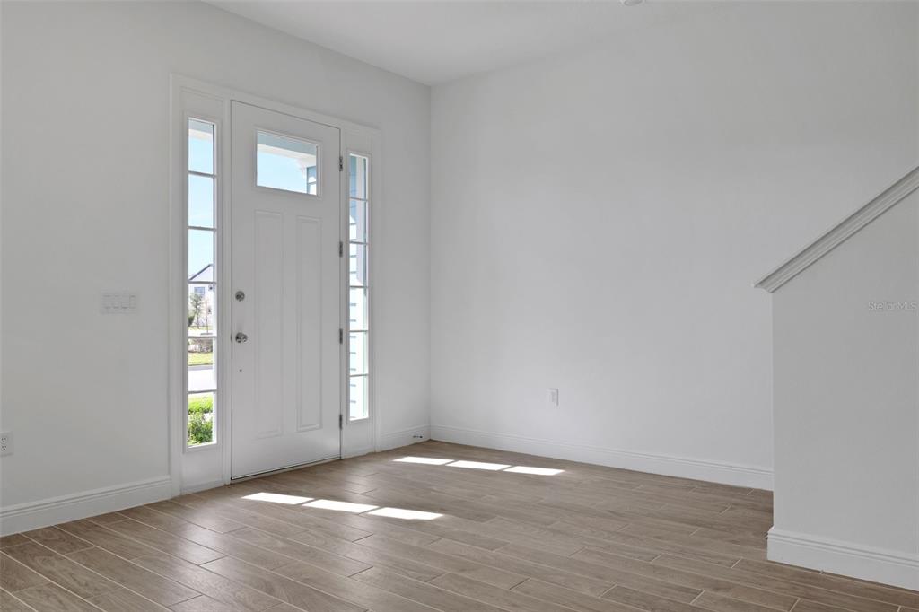 An entryway features a white front door with sidelights, white walls, and wood-look tile flooring — 6527 TRAILBLAZE BEND, ST CLOUD, FL