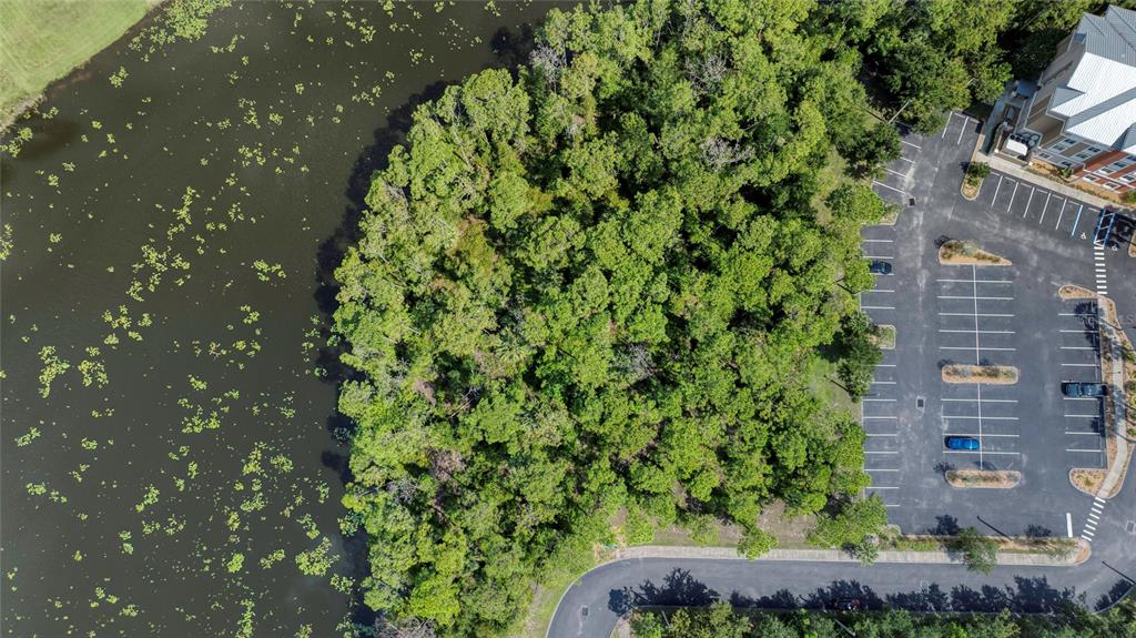 An aerial view shows a wooded lot situated between a parking lot and a pond — xxx GARDEN STREET N, PALM COAST, FL