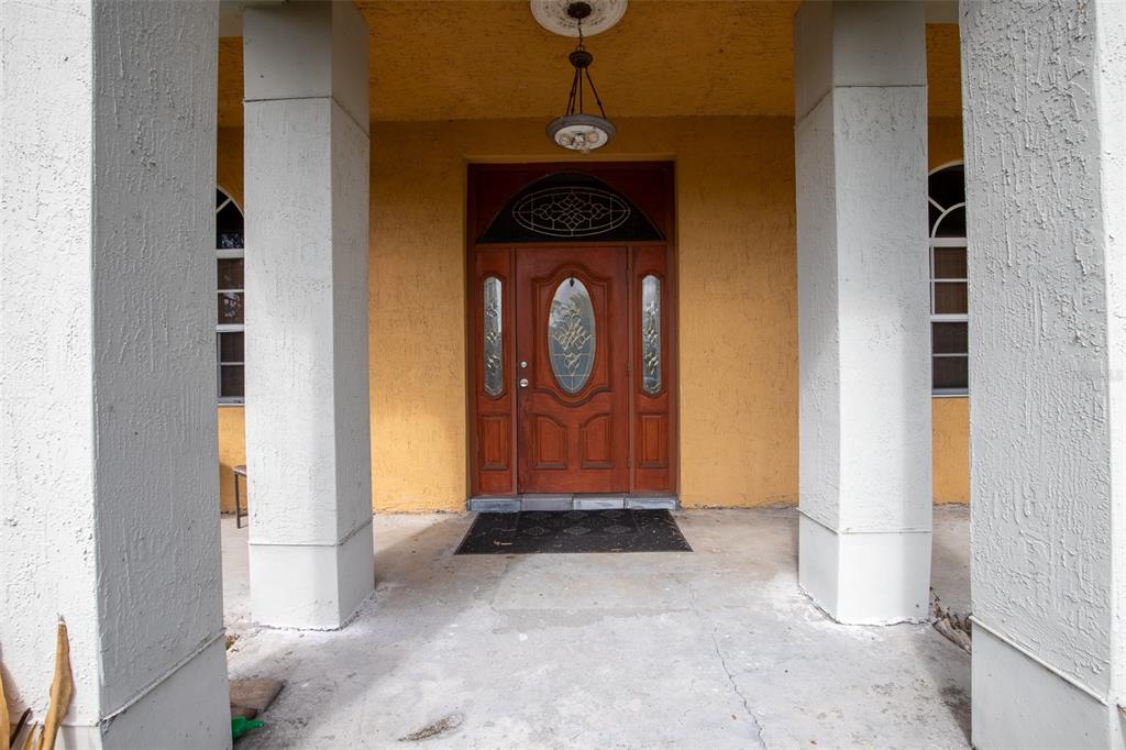 A covered front porch features a wooden door with glass inserts between two white columns — 687 MONTURA AVENUE, CLEWISTON, FL