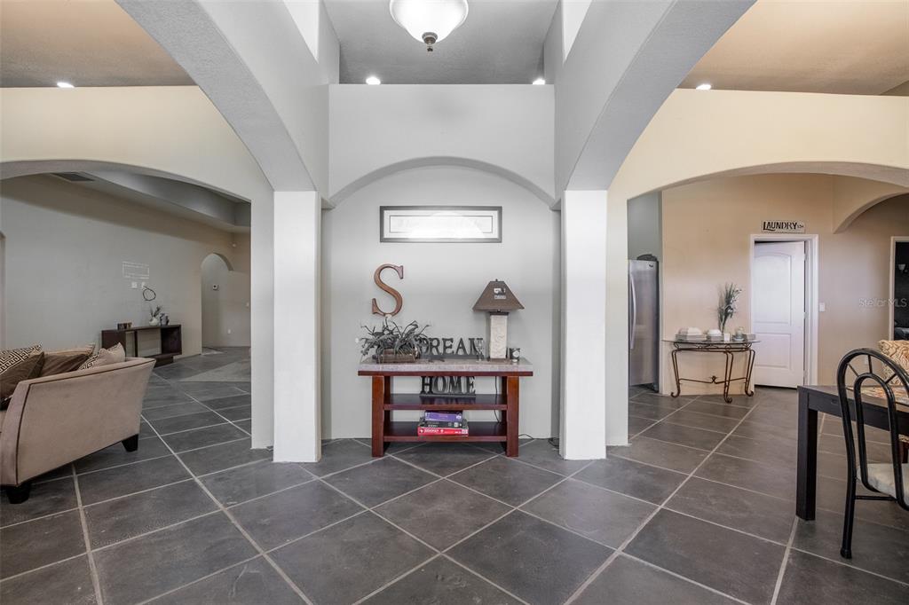 A spacious foyer features gray tile flooring, arched entryways, and a central console table — 687 MONTURA AVENUE, CLEWISTON, FL