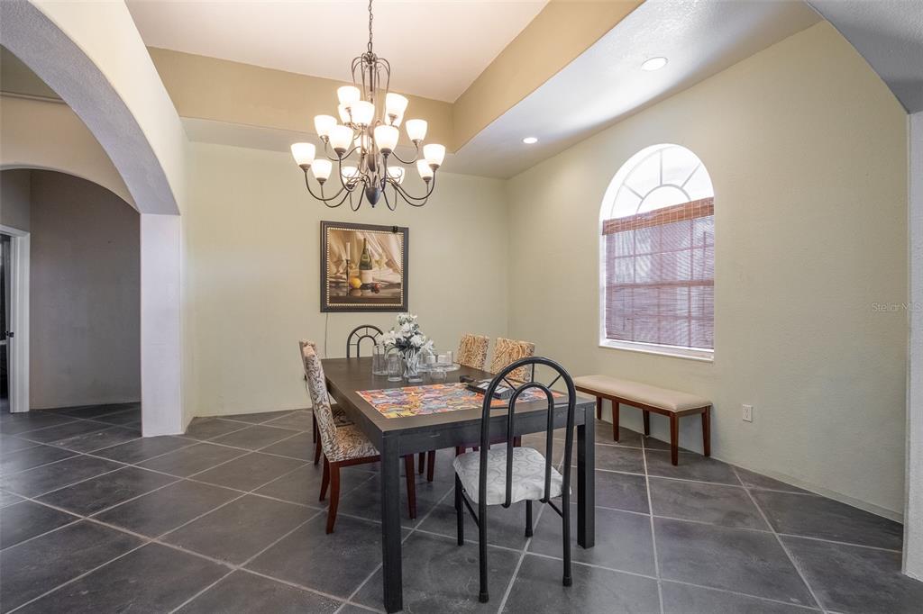 A dining room features a dark table, patterned chairs, a chandelier, and tile flooring — 687 MONTURA AVENUE, CLEWISTON, FL